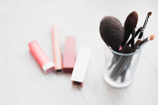 Lápices labiales cerca de pinceles de maquillaje