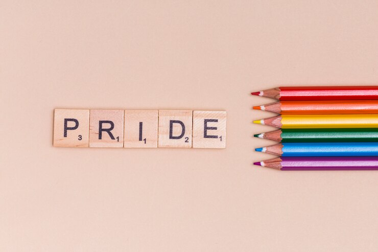 Foto gratuito lápices multicolores y texto orgullo sobre fondo beige
