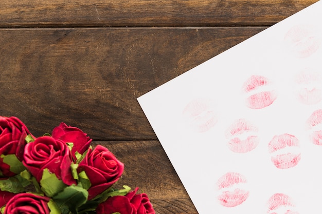 Foto gratuita lápiz labial besos en papel cerca de hermosas flores.