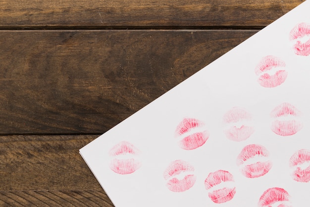 Foto gratuita lápiz labial besos en papel sobre tabla de madera