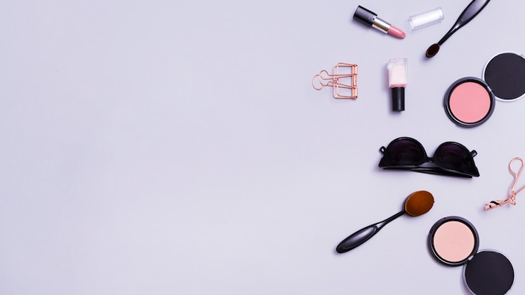Foto gratuito lápiz labial; esmalte de uñas; gafas de sol; brocha de maquillaje; gafas de sol; polvo de maquillaje compacto de la cara sobre fondo púrpura