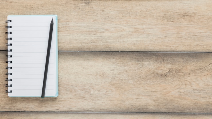 Foto gratuito lápiz sobre cuaderno abierto en escritorio de madera