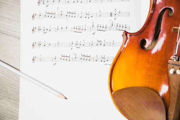 Foto gratuita lápiz y violín sobre la nota musical en la mesa