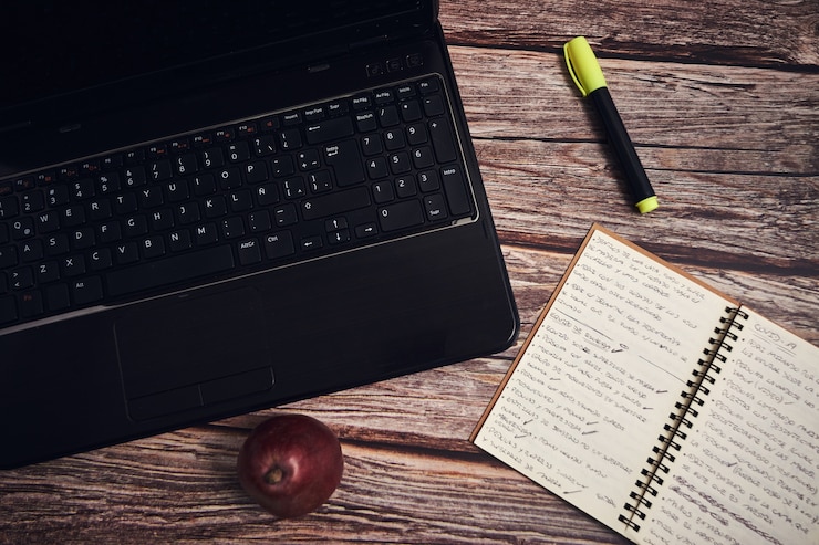 Photo Gratis laptop and a notebook on a wooden desk