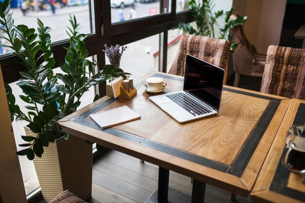 Laptop con bloc de notas en cafe en mesa