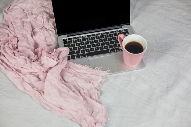 Laptop en cama con taza de café