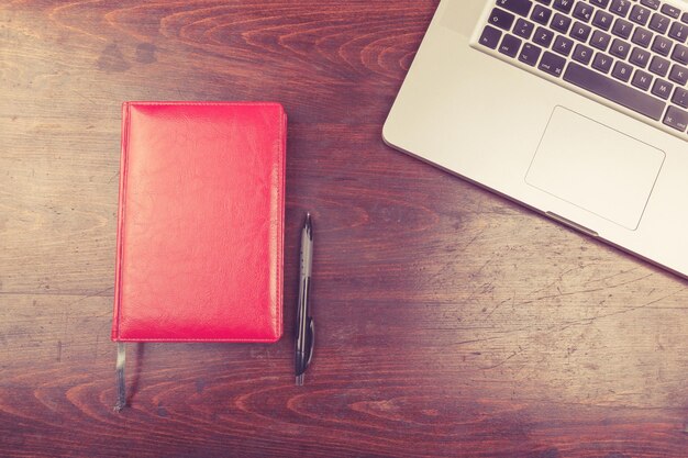 Laptop y un cuaderno para escribir desde arriba sobre un fondo de madera