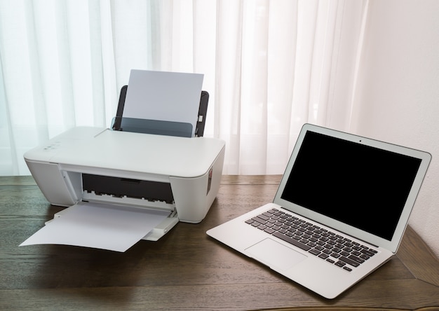 Laptop di atas meja kayu dengan printer
