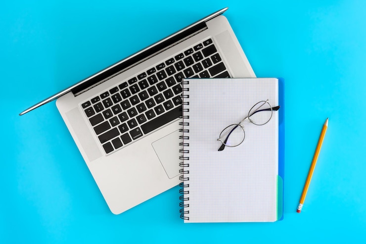 Foto gratuito laptop y gafas en blanco en un fondo azul