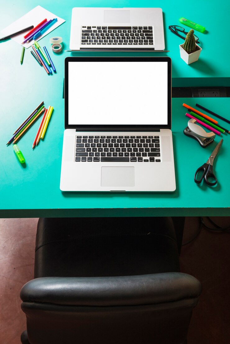 Foto gratuito laptop con pantalla blanca en blanco en mesa turquesa con silla cercana