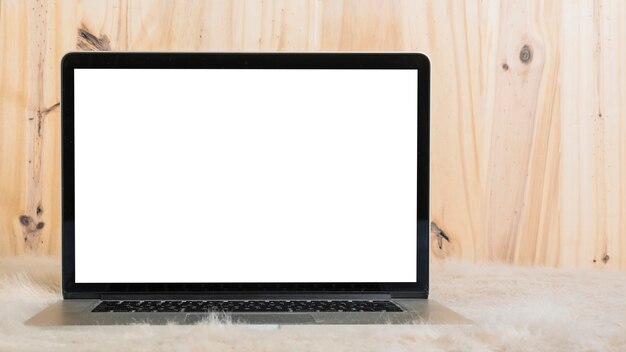 Laptop con pantalla blanca en blanco sobre piel suave