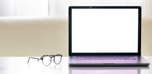 Foto gratuita laptop con una pantalla en blanco en una mesa blanca con gafas