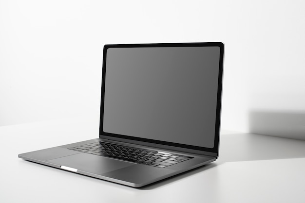 Laptop con pantalla negra en blanco en una mesa blanca