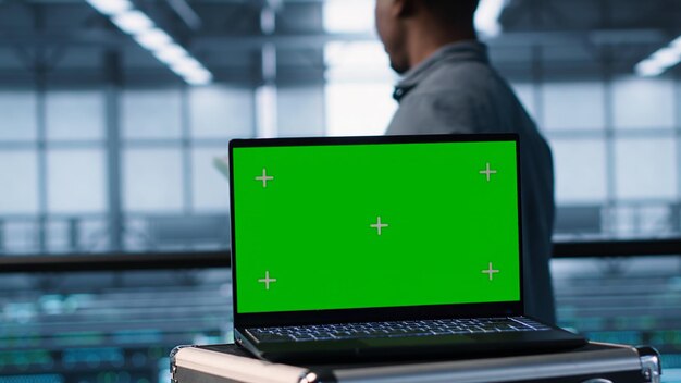 Laptop de pantalla verde frente a los ingenieros del centro de datos inspeccionando los servidores