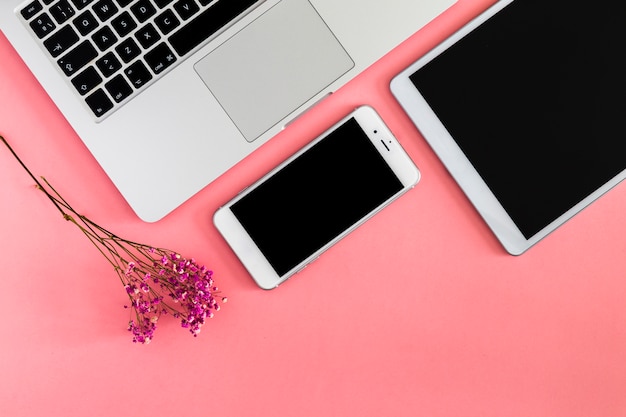 Laptop con tablet y smartphone en mesa rosa