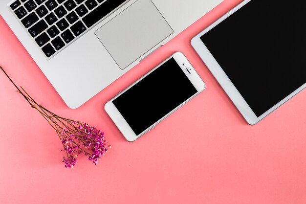 Laptop con tablet y smartphone en mesa rosa