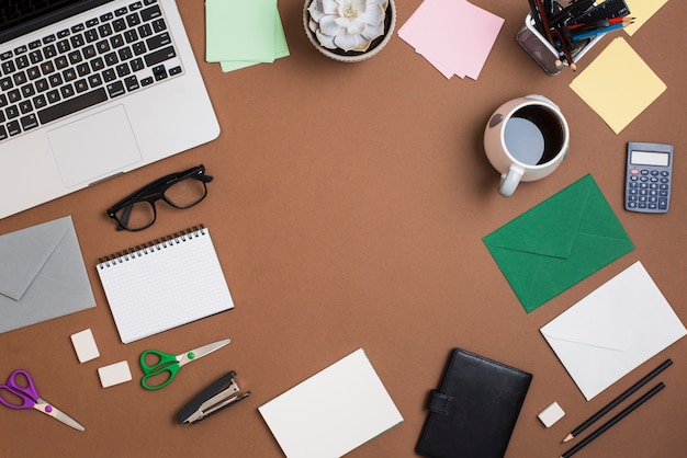 Laptop y taza de café con papelería en escritorio marrón