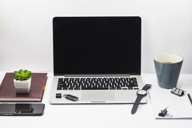 Laptop con taza de café y planta