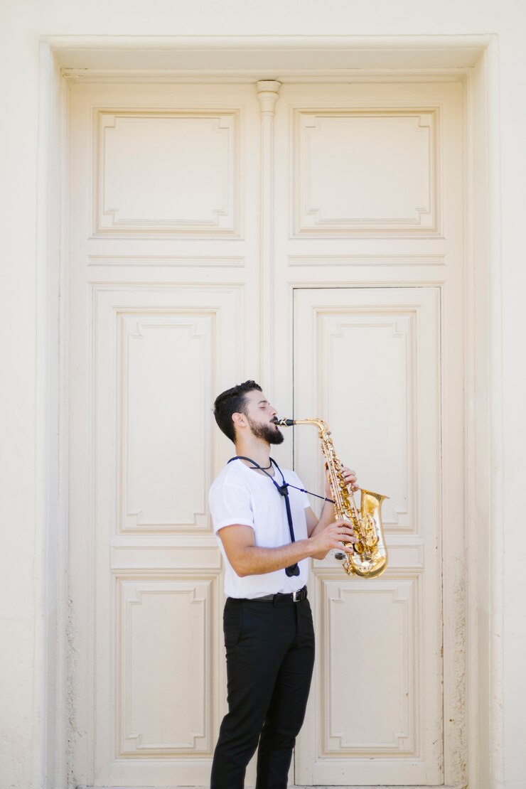 Foto gratuito largo tiro de lado músico tocando el saxofón.