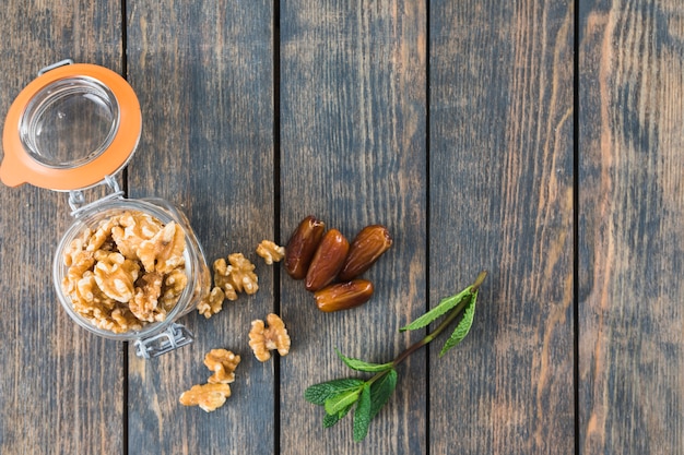 Lata con nueces cerca de ramita de plantas y frutos secos.