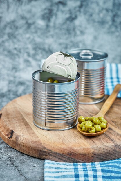 Latas de guisantes hervidos con una tabla de madera y una cuchara.