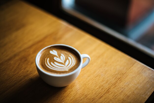 Latte art en taza de café en la mesa de café
