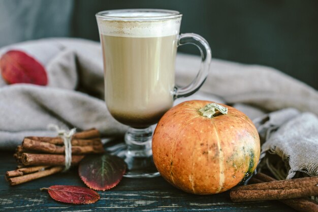 Latte de calabaza picante en una tabla de madera con un suéter