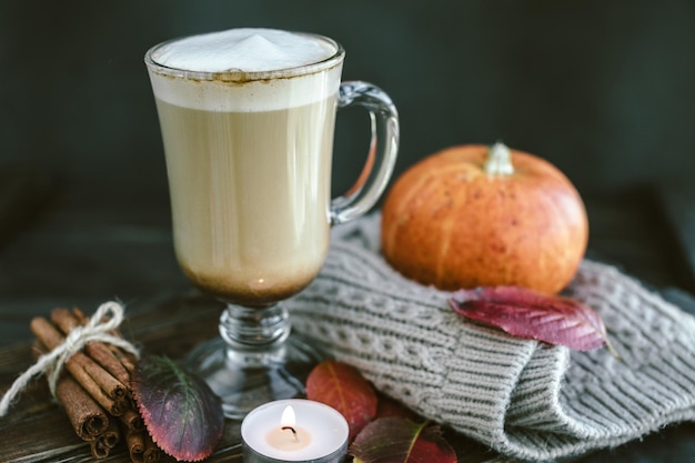 Latte de calabaza picante en una tabla de madera con un suéter