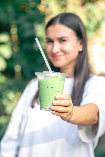 Latte matcha helado en un vaso de plástico en manos de una mujer