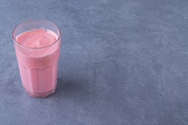 Latte de moca rosa con leche en un vaso, sobre la mesa de mármol