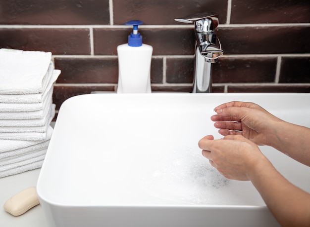 Lavarse las manos con agua corriente en el baño. El concepto de higiene y salud personal.