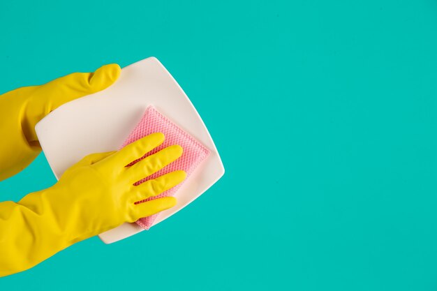 Lavavajillas con guantes amarillos sobre un azul.