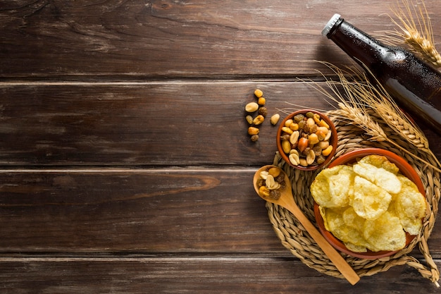 Foto gratuita lay flat de botella de cerveza con patatas fritas y nueces