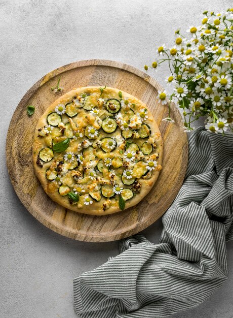 Lay Flat de deliciosa pizza cocida con ramo de flores de manzanilla