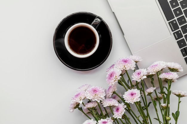 Foto gratuita lay flat con flores y portátil con taza de café.