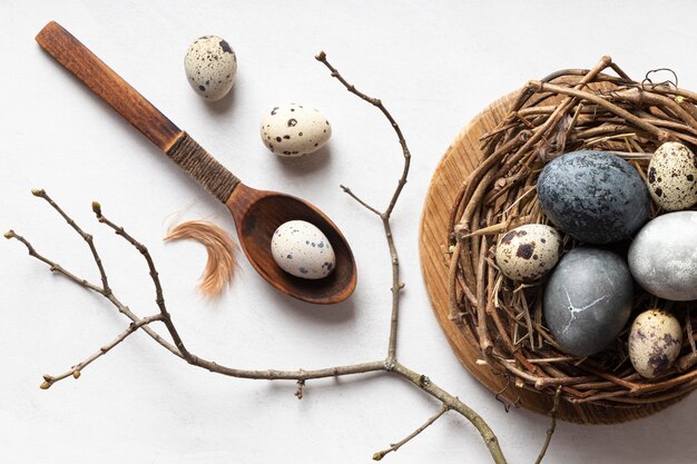 Lay Flat de huevos de pascua en nido de pájaro con cuchara de madera y ramita