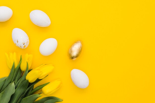 Foto gratuita lay flat de huevos de pascua con tulipanes y espacio de copia