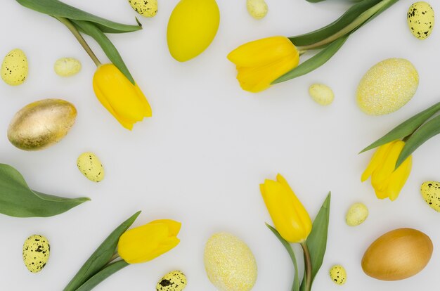 Foto gratuita lay flat de huevos de pascua con tulipanes