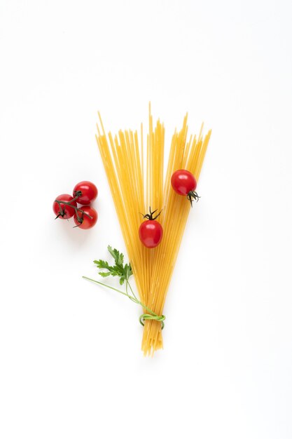 Lay Flat de ingredientes de espaguetis crudos dispuestos como un ramo sobre la superficie blanca