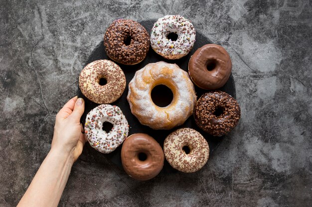 Lay Flat de mano sujetando un plato de donas