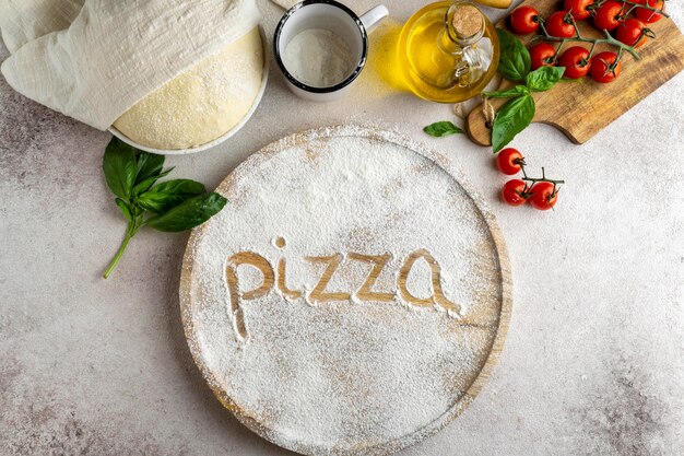 Lay Flat de masa de pizza con tablero de madera y palabra escrita en harina
