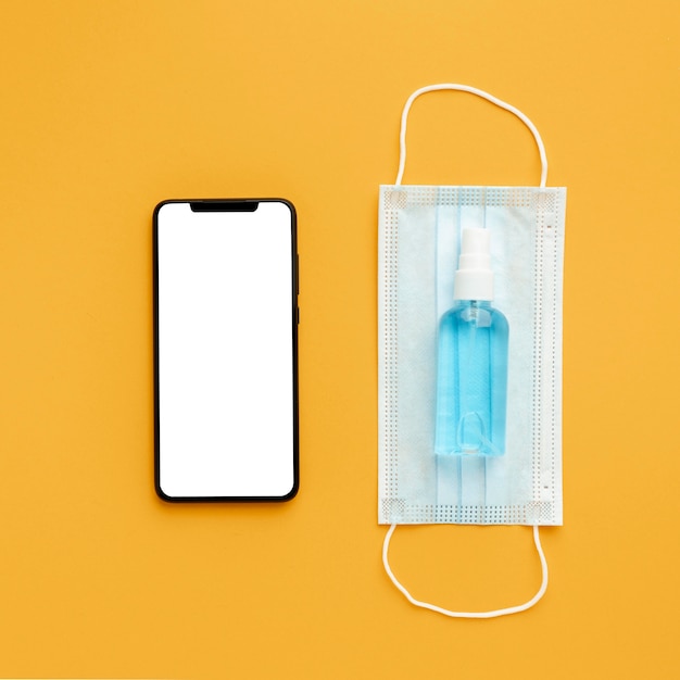 Lay Flat de mascarilla médica con smartphone y desinfectante de manos