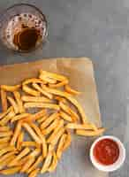 Foto gratuita lay flat de papas fritas con salsa de tomate y bebida gaseosa