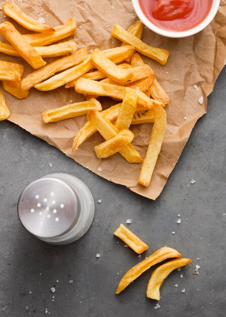 Lay Flat de papas fritas sobre papel con sal y salsa de tomate