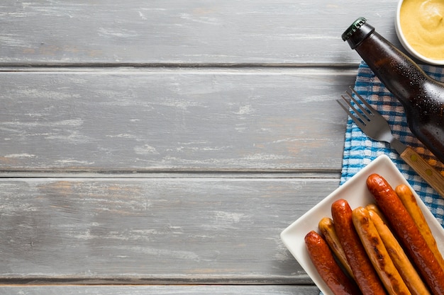 Foto gratuita lay flat de salchichas con botella de cerveza y espacio de copia