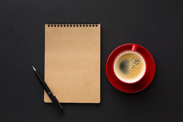 Lay Flat de taza de café y cuaderno en la mesa de trabajo