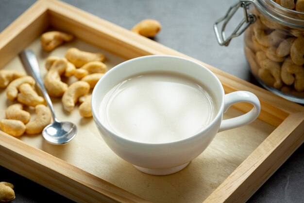 Leche de anacardo vegana en vaso con anacardos sobre fondo oscuro