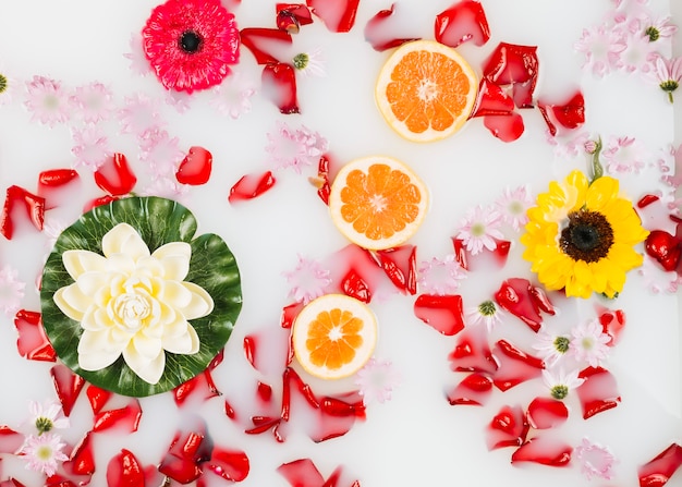 Leche de baño decorada maravillosamente con flores, pétalos y rodajas de pomelo