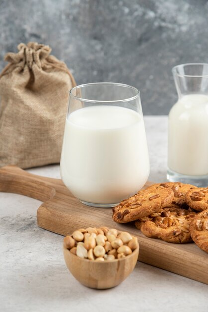 Leche fresca y galletas en la tabla de cortar de madera con maní.