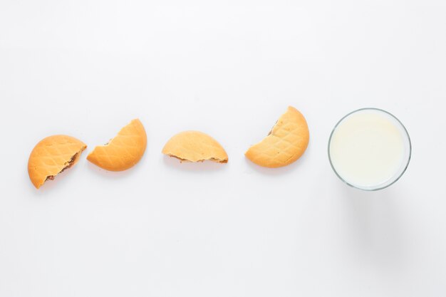 Leche y galletas dispuestas en una fila para el desayuno de la mañana sobre fondo blanco